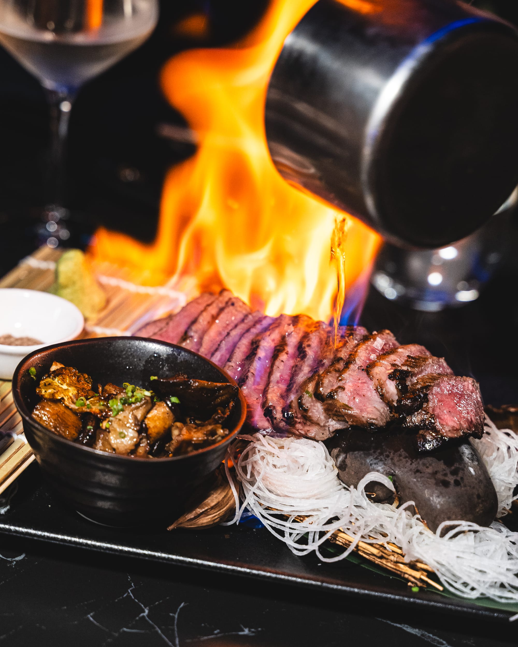 Sizzling beef steak served on a hot plate with flames in the background