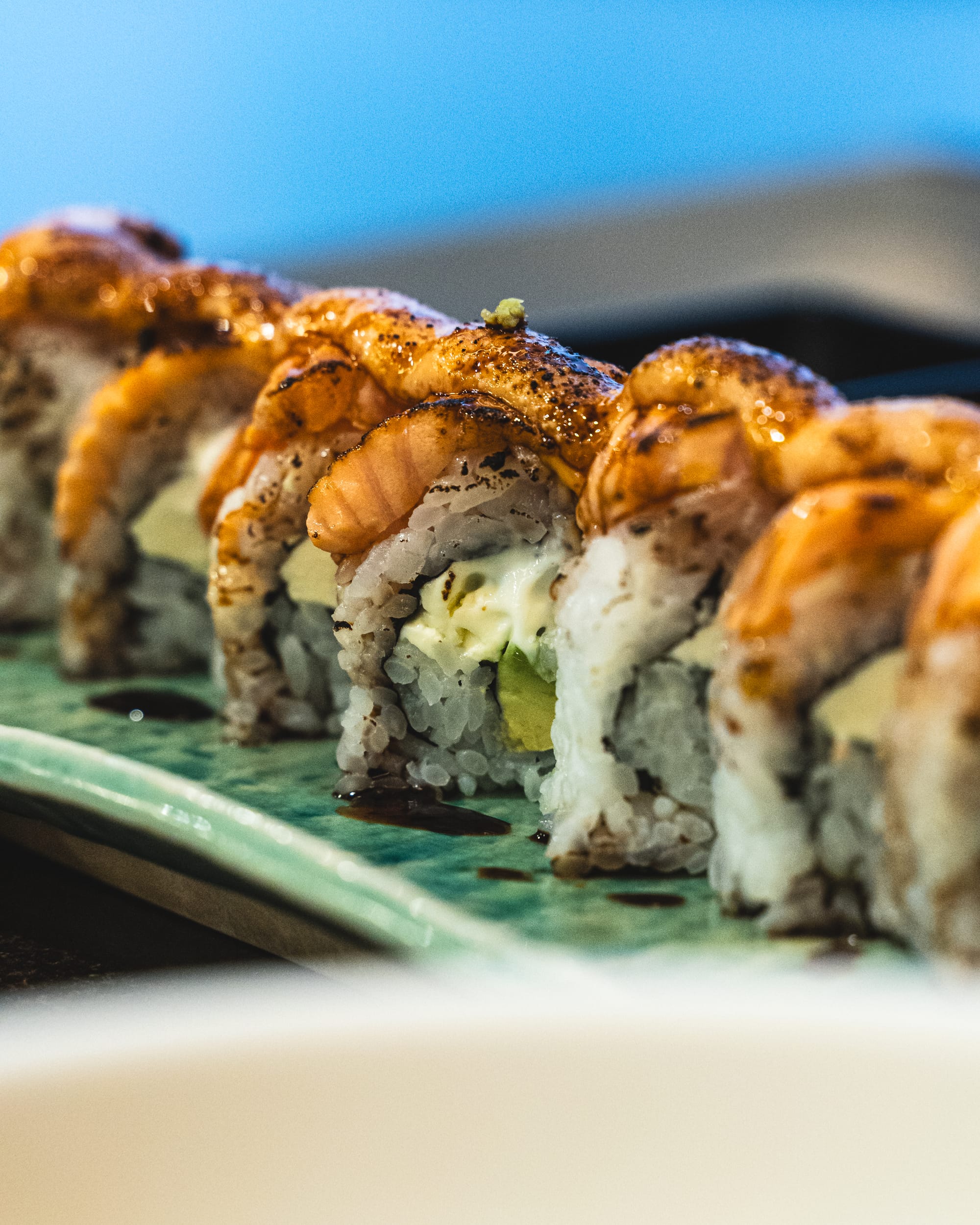 A sushi roll with various toppings, served on a glass plate.