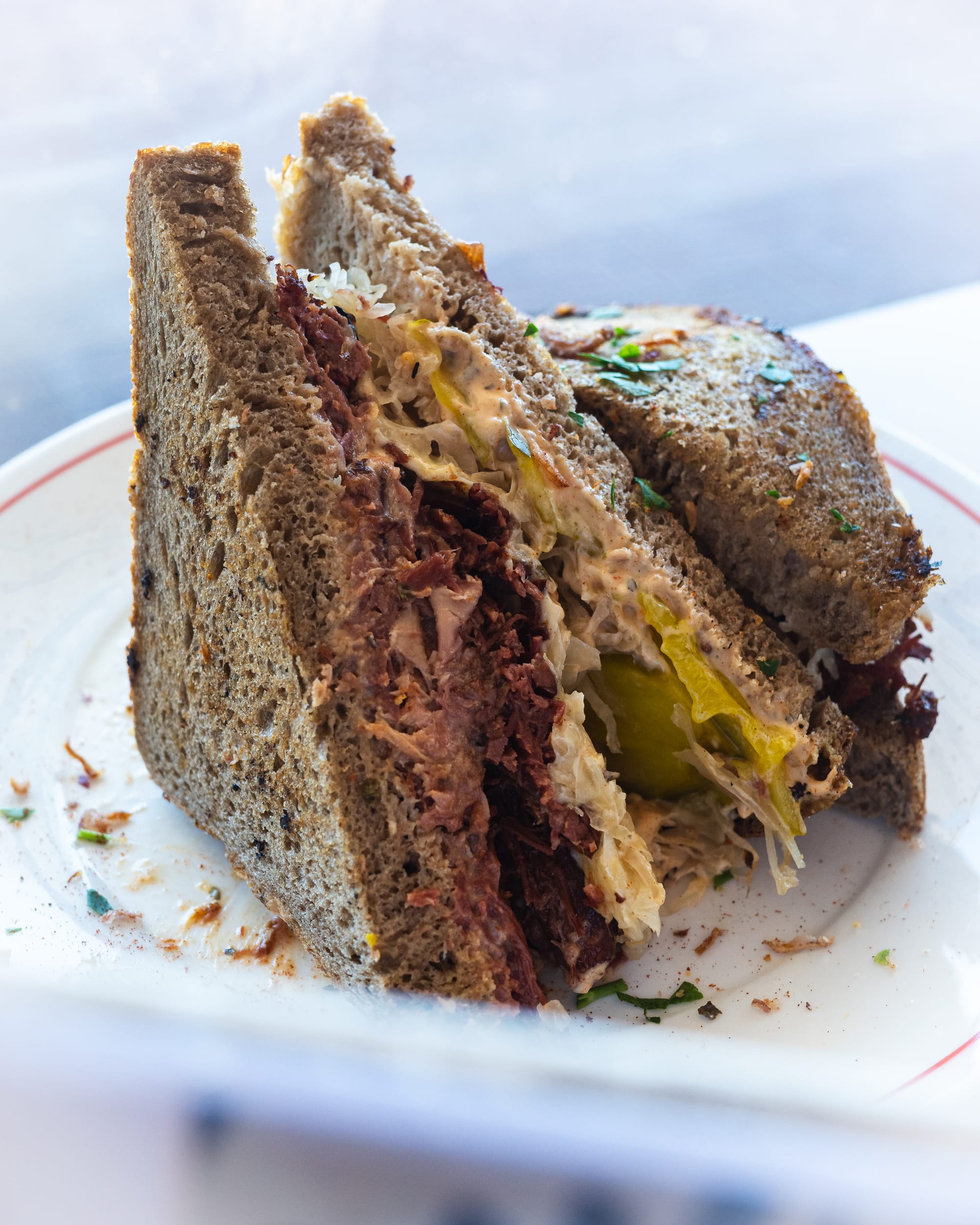 A close-up of a Reuben sandwich with corned beef, sauerkraut, and pickles on rye bread.