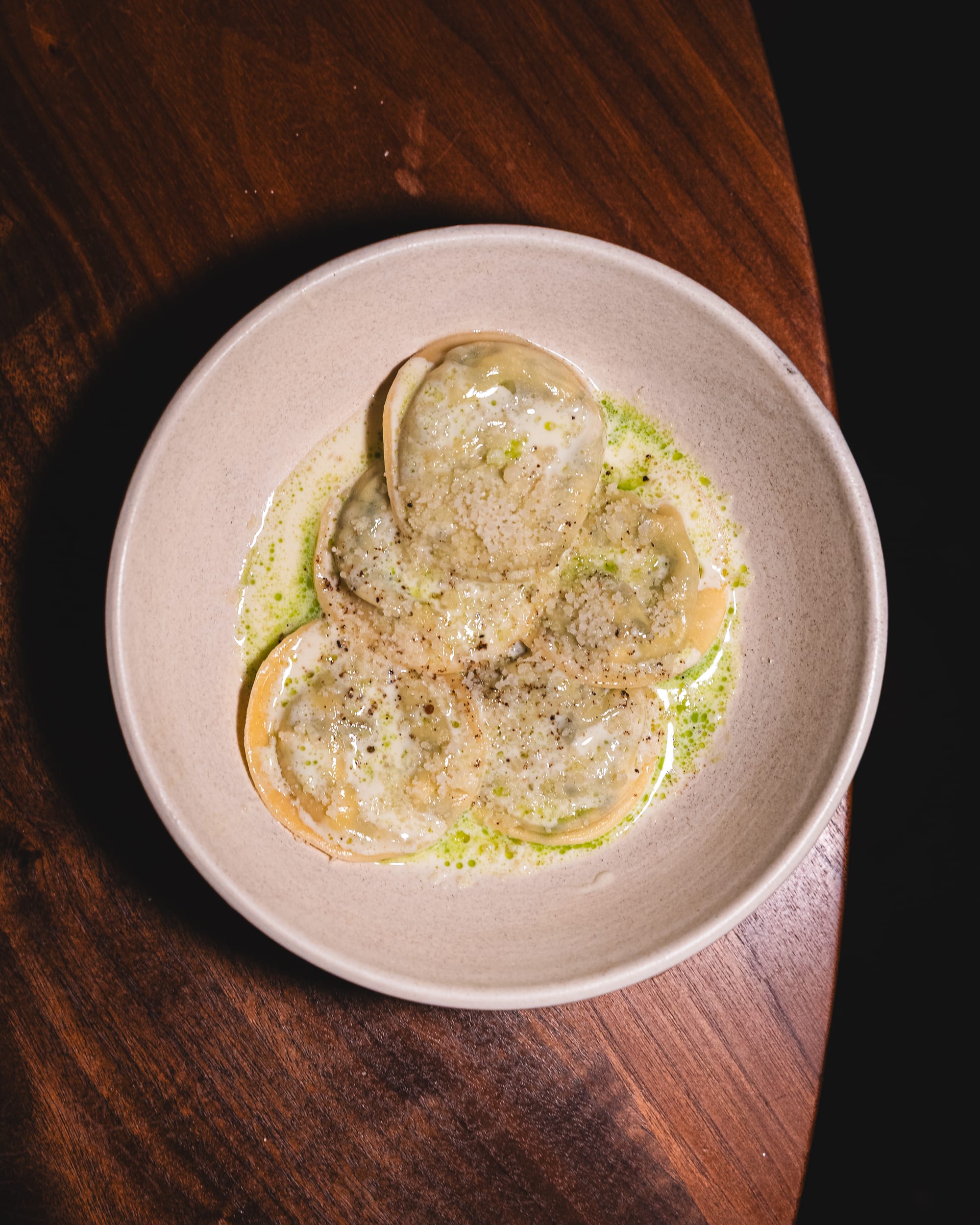 A plate of ravioli-style pasta with a light creamy sauce, garnished with herbs.