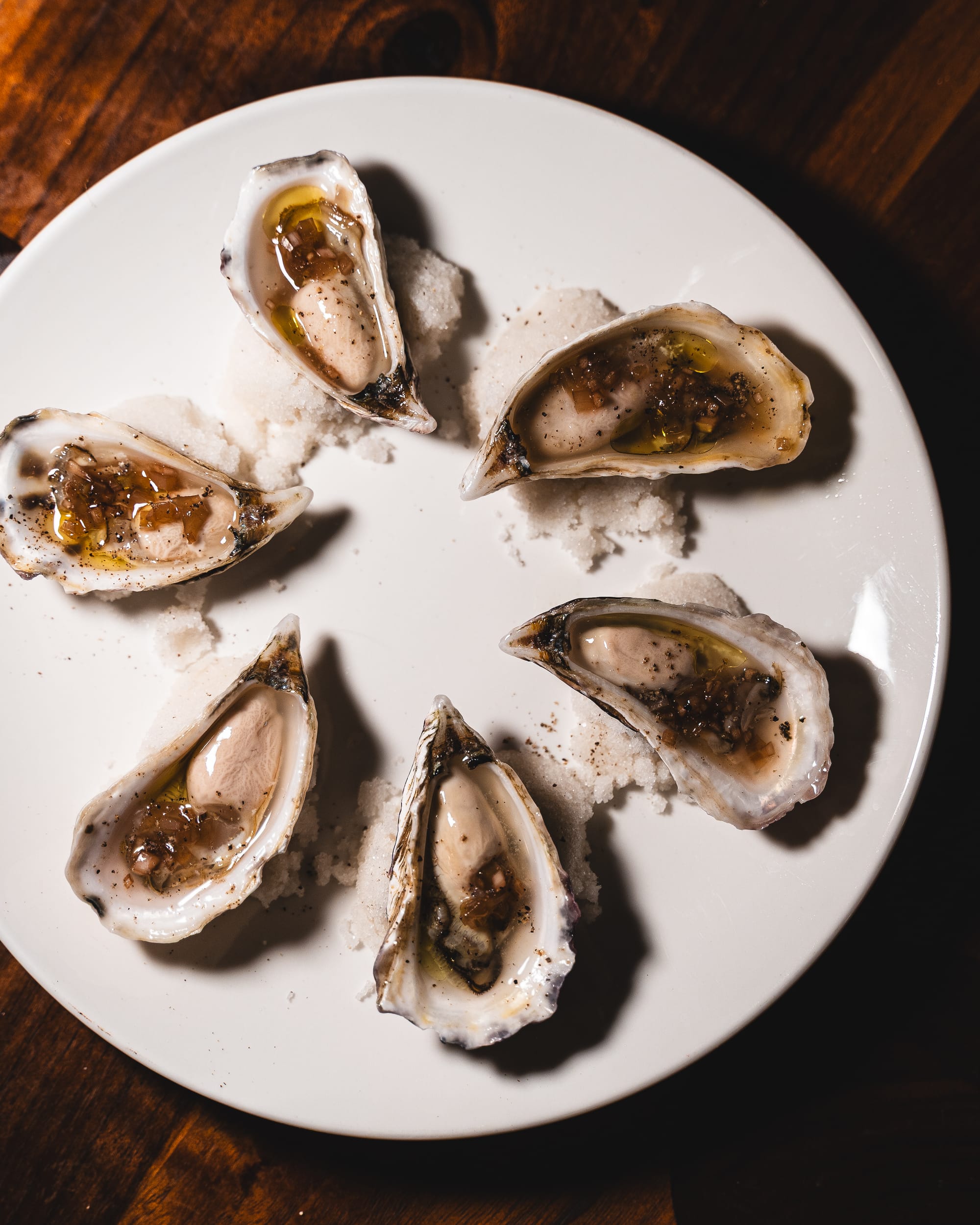 A plate of fresh oysters on the half shell, garnished with seasoning and sauce.