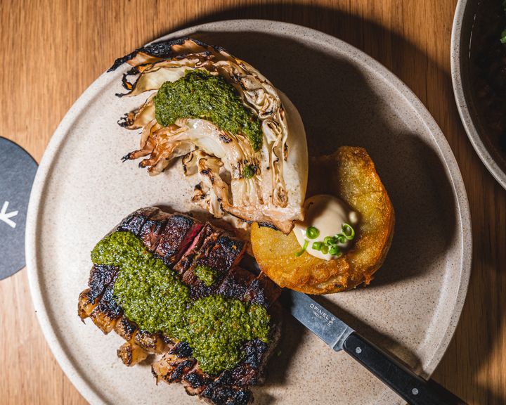 Top down shot of sirloin steak with chimichuri, potato and roasted cabbage