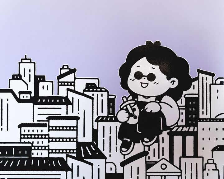 Cartoon drawing on wall of a city skyline with a cartoon character resting on buildings