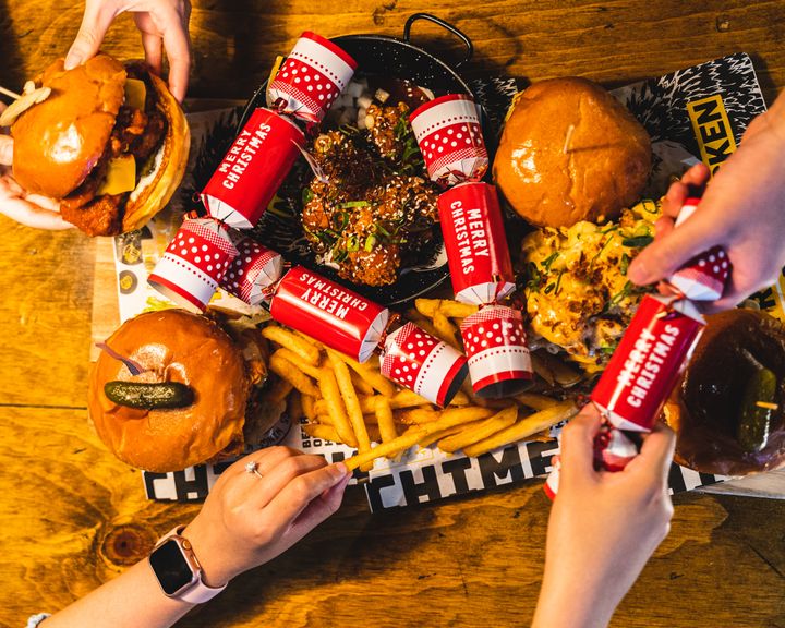 Overhead shot of people reaching into a platter for burgers and chips