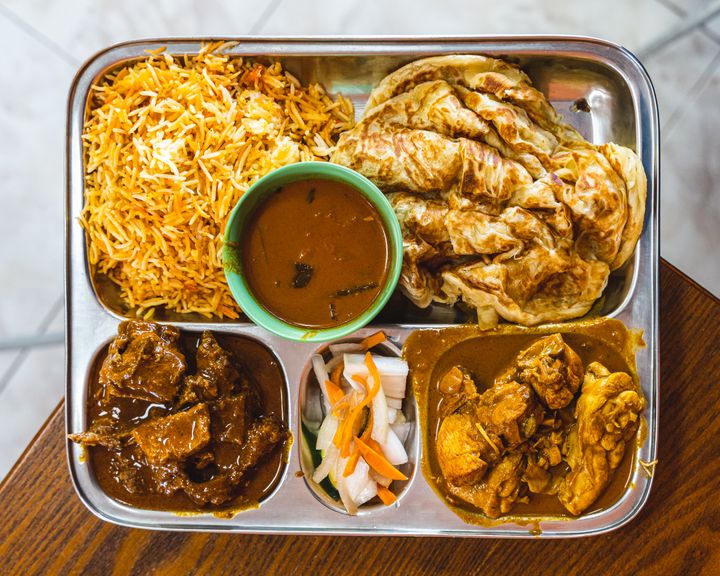 Top down of curry on a silver tray with roti and briyani