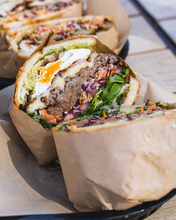 Close up of arepa with egg, beef patty and salad