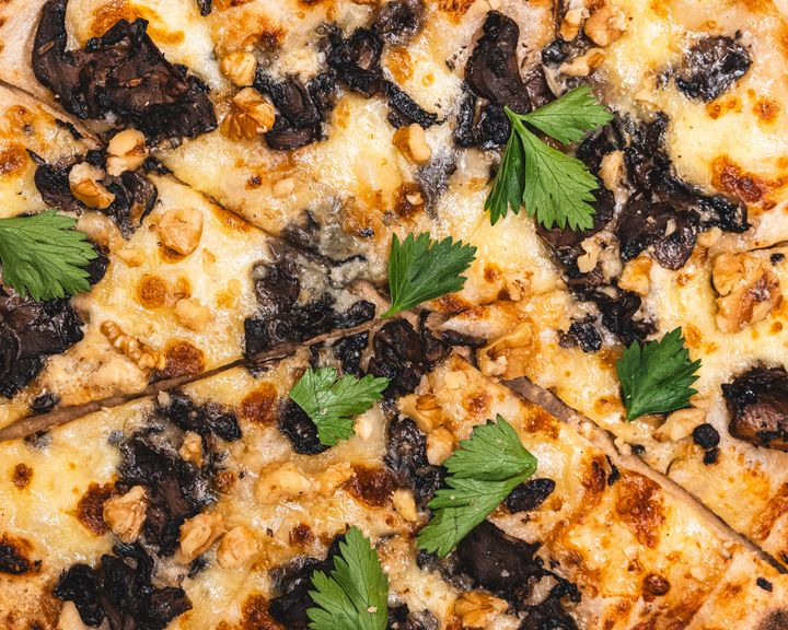 Close up of pizza with fior di latte, blue cheese, mushrooms, walnuts and parsley