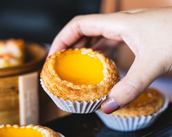 Manicured hand holding an egg tart