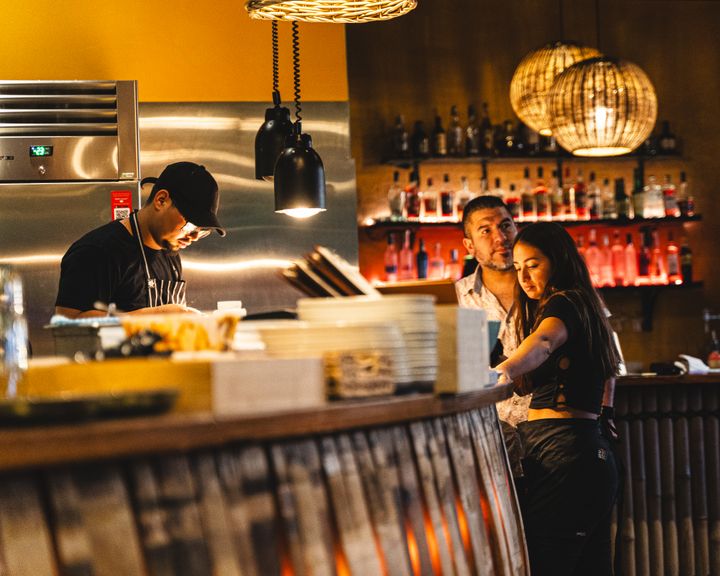 Candid photo of staff waiting by a kitchen counter inside of a restaurant