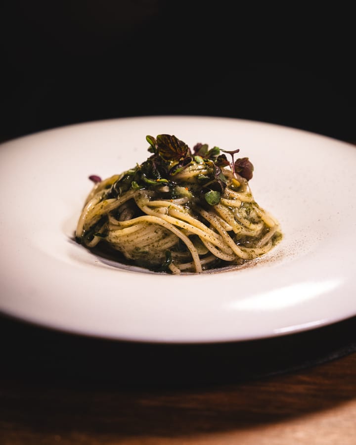 Close up of spaghetti with greens and a dusting of powder