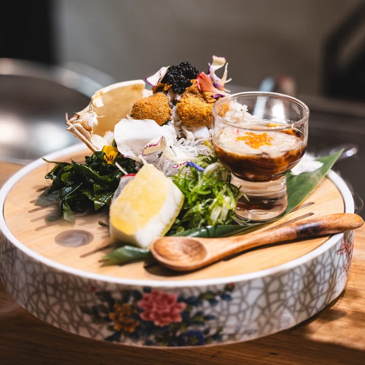 Close up of platter with lemon, uni, caviar and salad with a wooden spoon